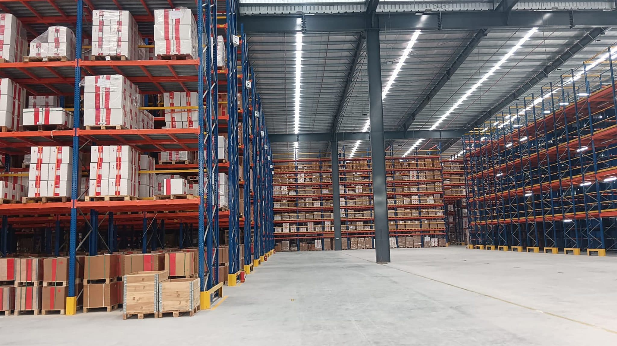 Tall pallet racking stacked with cartons inside a large warehouse